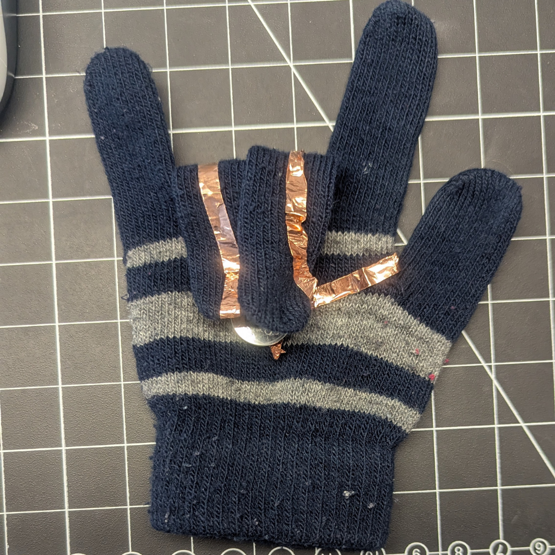 There is another side where the battery is located. Basically, I wanted this design to be fun, where whatever finger touches the battery would light up. It ended up looking like a Rockstar fan merch you could take to a concert, but I still wish I had made a better wearable design.